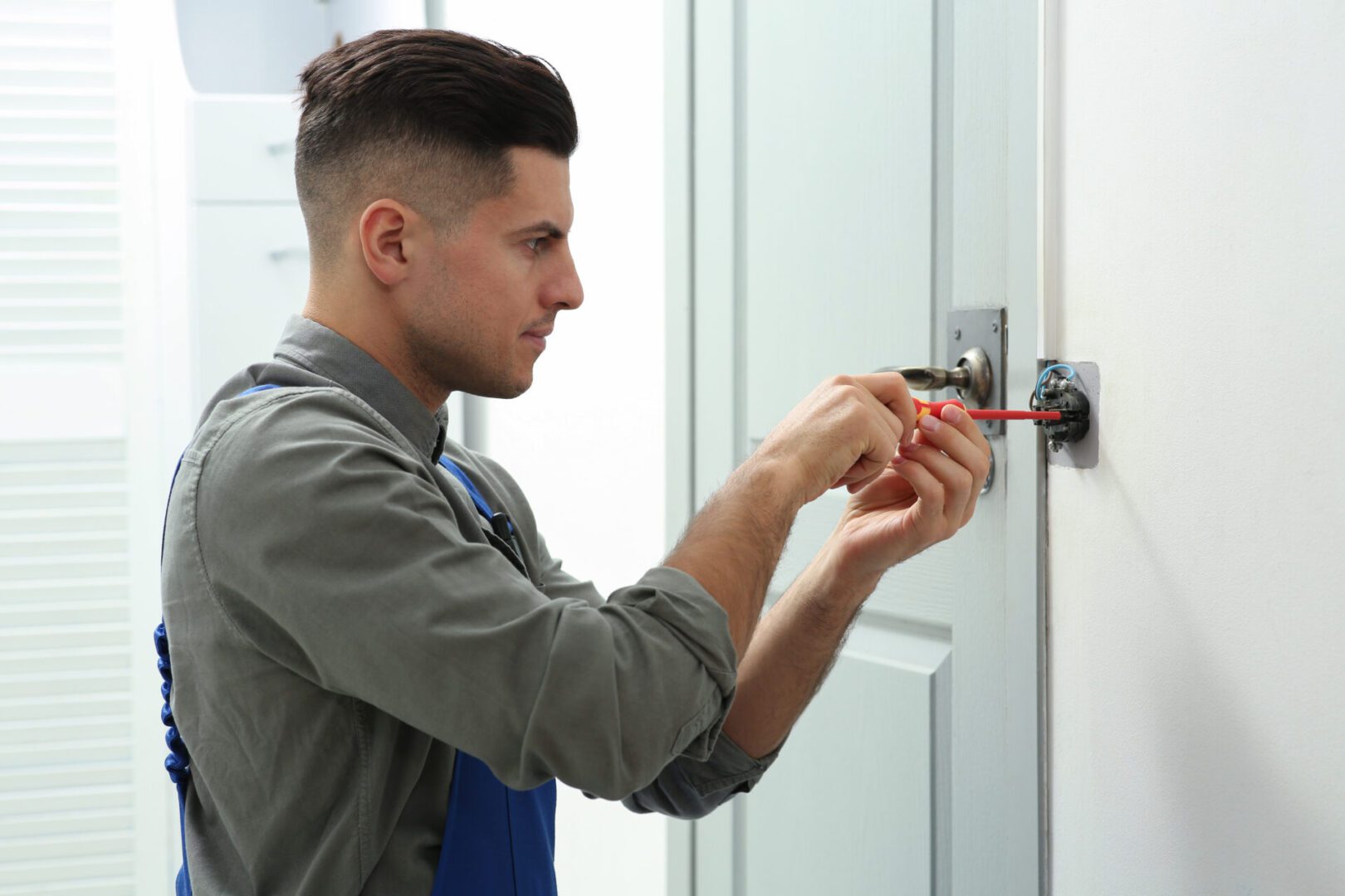 Man fixing door lock with screwdriver.