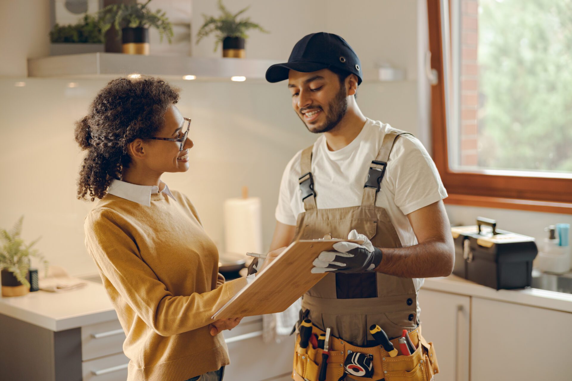 Woman and handyman discussing kitchen repairs.