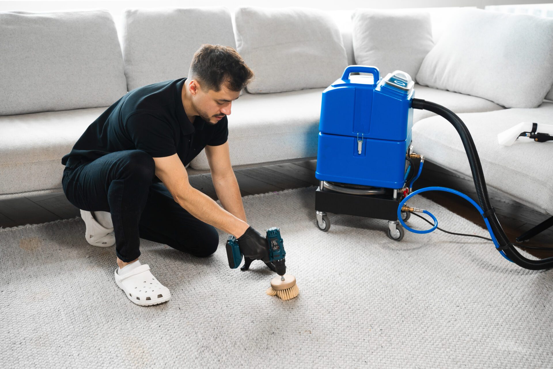 Man cleaning carpet with brush and machine.