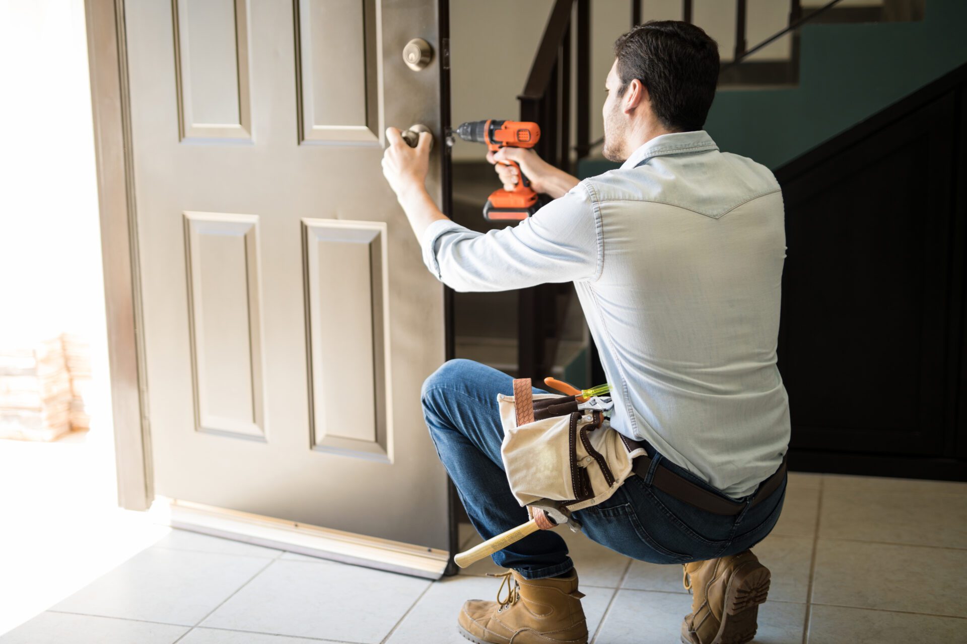 Man installing door lock with drill.